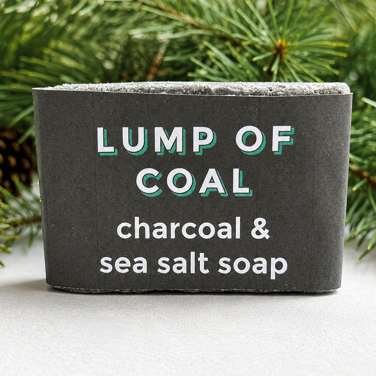 Cape Lilly Lump of Coal charcoal and sea salt soap in holiday wrapper with pine branches